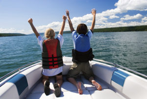 Two kids in the bow of a motorboat acting out a scene from the movie "Titanic".